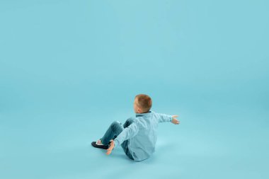 Çocukluk ve büyük ve ünlü bir gelecek hayal etmek. Güzel küçük çocuk mavi arka planda izole edilmiş