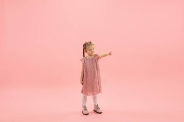 Çocukluk ve büyük ve ünlü bir gelecek hayal etmek. Mercan pembe arka planda izole edilmiş güzel uzun saçlı kız.