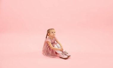 Çocukluk ve büyük ve ünlü bir gelecek hayal etmek. Mercan pembe arka planda izole edilmiş güzel uzun saçlı kız.