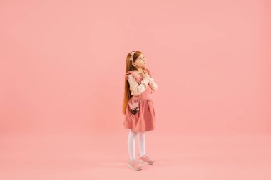 Çocukluk ve büyük ve ünlü bir gelecek hayal etmek. Mercan pembe arka planda izole edilmiş güzel uzun saçlı kız.