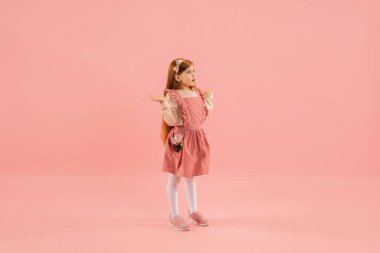 Çocukluk ve büyük ve ünlü bir gelecek hayal etmek. Mercan pembe arka planda izole edilmiş güzel uzun saçlı kız.