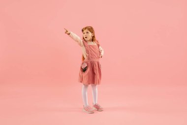 Çocukluk ve büyük ve ünlü bir gelecek hayal etmek. Mercan pembe arka planda izole edilmiş güzel uzun saçlı kız.