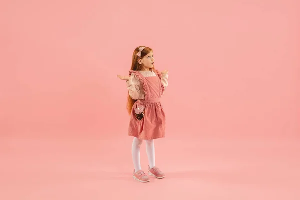 Kindheit und Traum von einer großen und berühmten Zukunft. Hübsches langhaariges Mädchen isoliert auf korallenrosa Hintergrund — Stockfoto