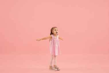 Çocukluk ve büyük ve ünlü bir gelecek hayal etmek. Mercan pembe arka planda izole edilmiş güzel uzun saçlı kız.