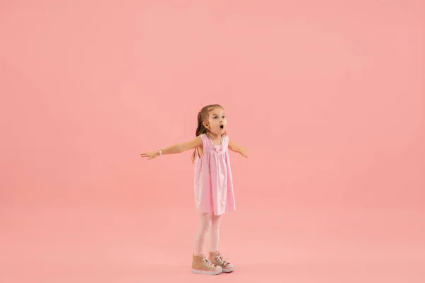 Infancia y sueño sobre el futuro grande y famoso. Bastante longhair chica aislado en coral rosa fondo — Foto de Stock
