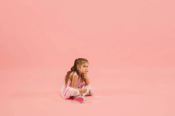 Детство и мечта о большом и знаменитом будущем. Красивая девушка длинные волосы изолированы на коралловом розовом фоне — стоковое фото