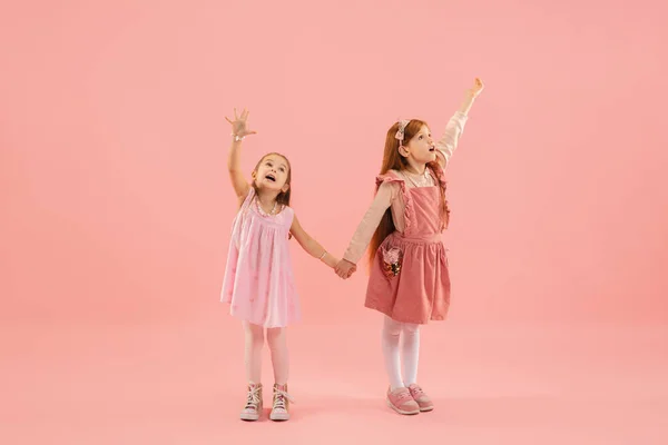 Infancia y sueño sobre el futuro grande y famoso. Niñas bonitas aisladas sobre fondo rosa coral — Foto de Stock