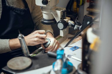 Mücevhercilerin, kuyumcuların, altın yüzüklerden profesyonel aletler kullanan kuyumcuların ellerini kapatın..