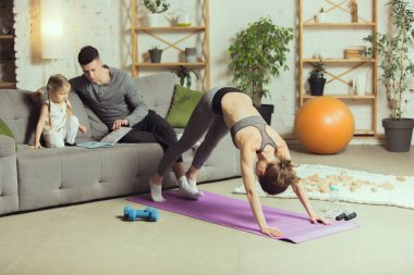Spor yapan genç bir kadın, aerobik, evde yoga, spor yaşam tarzı. Tecrit sırasında aktif hale gelip karantinaya alınıyor. Evde spor salonu.