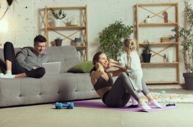 Spor yapan genç bir kadın, aerobik, evde yoga, spor yaşam tarzı. Tecrit sırasında aktif hale gelip karantinaya alınıyor. Evde spor salonu.