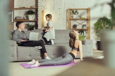 Spor yapan genç bir kadın, aerobik, evde yoga, spor yaşam tarzı. Tecrit sırasında aktif hale gelip karantinaya alınıyor. Evde spor salonu.