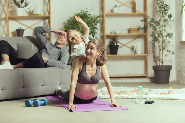 Mujer joven ejercitando fitness, aeróbico, yoga en casa, estilo de vida deportivo. Activarse durante el encierro, cuarentena. Gimnasio. — Foto de Stock