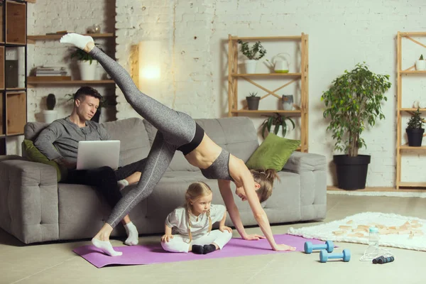Mujer joven ejercitando fitness, aeróbico, yoga en casa, estilo de vida deportivo. Activarse durante el encierro, cuarentena. Gimnasio. — Foto de Stock