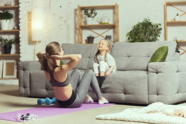 Spor yapan genç bir kadın, aerobik, evde yoga, spor yaşam tarzı. Tecrit sırasında aktif hale gelip karantinaya alınıyor. Evde spor salonu.