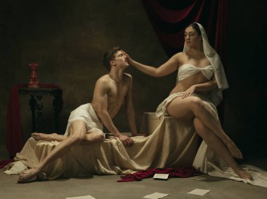 Klasik sanatın modern yeniden çekimi - karanlık arka planda genç bir ortaçağ çifti, dönemin konseptiyle karşılaştırma