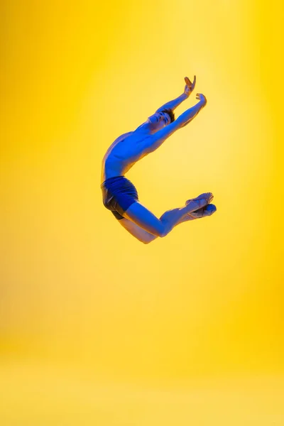 Young and graceful ballet dancer isolated on yellow studio background in neon light. Art, motion, action, flexibility, inspiration concept. — Stock Photo, Image