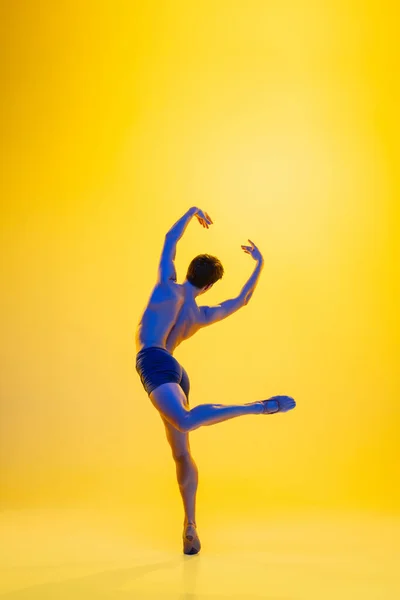 Mladý a půvabný baletní tanečník izolovaný na žlutém pozadí studia v neonovém světle. Umění, pohyb, akce, flexibilita, inspirace. — Stock fotografie
