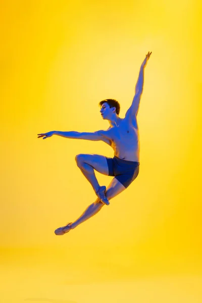 Молода і витончена балетна танцівниця ізольована на жовтому студійному фоні в неоновому світлі. Мистецтво, рух, дія, гнучкість, концепція натхнення . — стокове фото