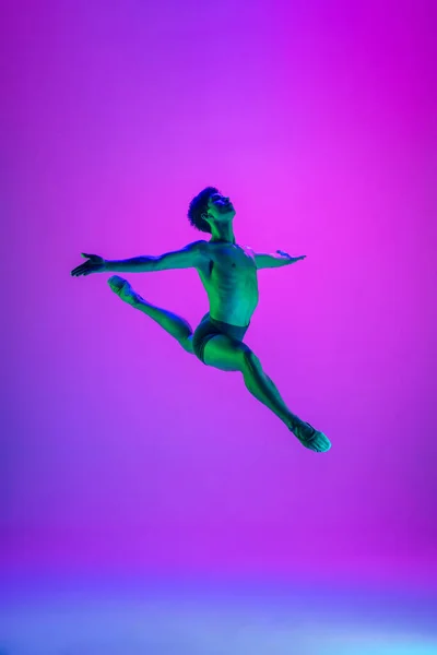 Jonge en sierlijke balletdanser geïsoleerd op paarse studioachtergrond in neonlicht. Kunst, beweging, actie, flexibiliteit, inspiratie. — Stockfoto