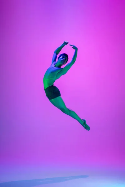 Jonge en sierlijke balletdanser geïsoleerd op paarse studioachtergrond in neonlicht. Kunst, beweging, actie, flexibiliteit, inspiratie. — Stockfoto