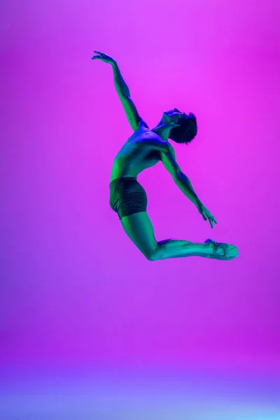 Jovem e graciosa dançarina de balé isolado no fundo do estúdio roxo em luz de néon. Arte, movimento, ação, flexibilidade, conceito de inspiração. — Fotografia de Stock