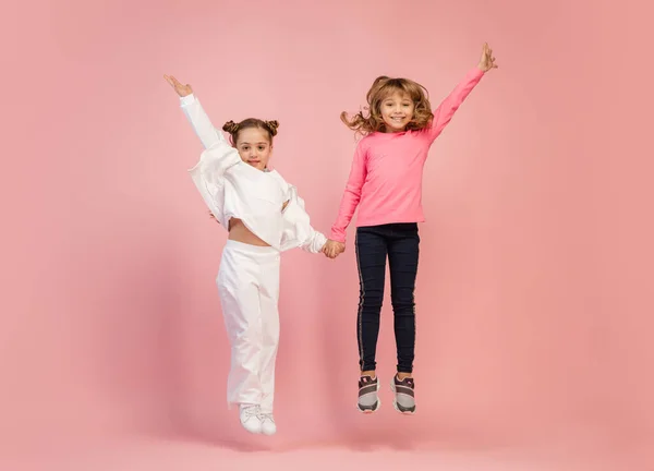 Des enfants heureux, des filles isolées sur fond de studio rose corail. Regardez heureux, joyeux, sincère. Copyspace. Enfance, éducation, concept des émotions — Photo