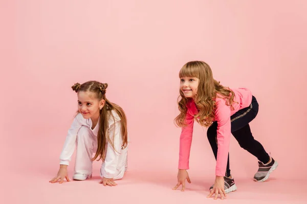 Crianças felizes, meninas isoladas no fundo do estúdio coral rosa. Pareces feliz, alegre, sincero. Espaço de cópia. Infância, educação, conceito de emoções — Fotografia de Stock