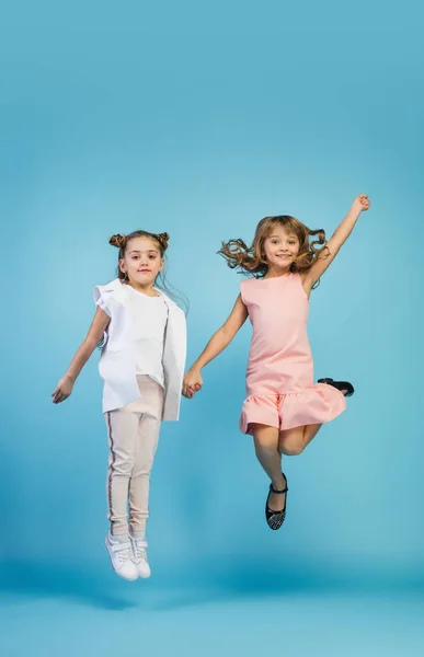 Niños felices, chicas aisladas en el fondo azul del estudio. Parecen felices, alegres, sinceros. Copyspace. Infancia, educación, concepto de emociones — Foto de Stock