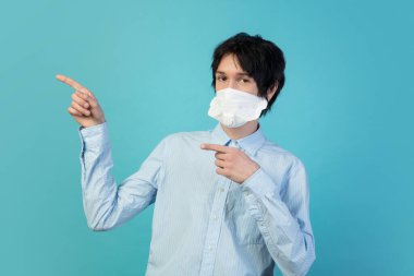 Mavi stüdyo arka planında, koruyucu maskeli bir adam izole edilmiş. Yeni COVID kuralları önlemeyi yayıyor