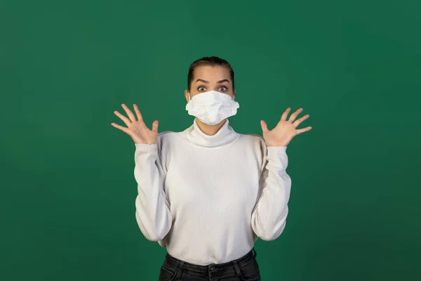 Mujer con mascarilla protectora aislada sobre fondo de estudio verde. Nuevas normas de prevención de la propagación de COVID — Foto de Stock
