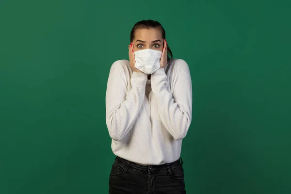 Mujer con mascarilla protectora aislada sobre fondo de estudio verde. Nuevas normas de prevención de la propagación de COVID — Foto de Stock