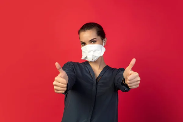 Mujer con mascarilla protectora aislada sobre fondo rojo estudio. Nuevas normas de prevención de la propagación de COVID — Foto de Stock