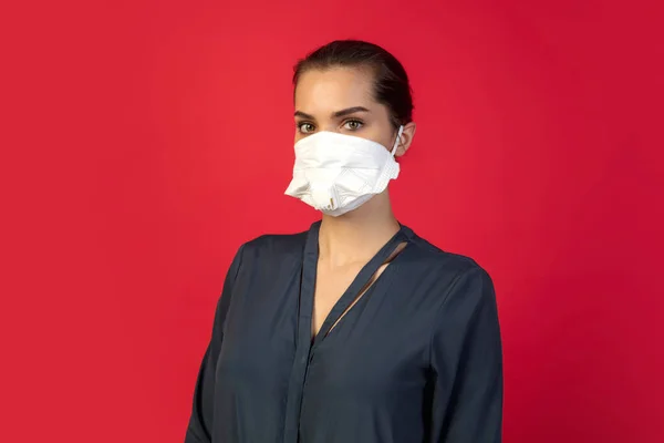 Mujer con mascarilla protectora aislada sobre fondo rojo estudio. Nuevas normas de prevención de la propagación de COVID — Foto de Stock