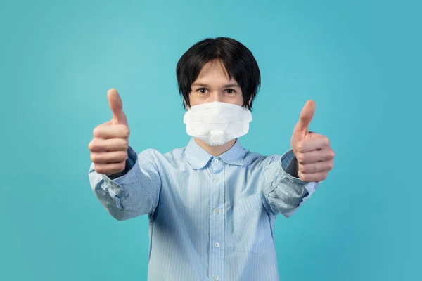 Hombre con mascarilla protectora aislado sobre fondo azul estudio. Nuevas normas de prevención de la propagación de COVID — Foto de Stock