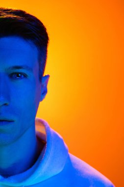 Beyaz erkek portresi sarı stüdyo arka planında çok renkli neon ışıklarıyla izole edilmiş.