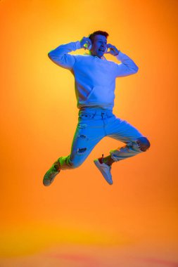 Beyaz erkek portresi sarı stüdyo arka planında çok renkli neon ışıklarıyla izole edilmiş.