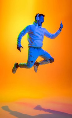 Beyaz erkek portresi sarı stüdyo arka planında çok renkli neon ışıklarıyla izole edilmiş.