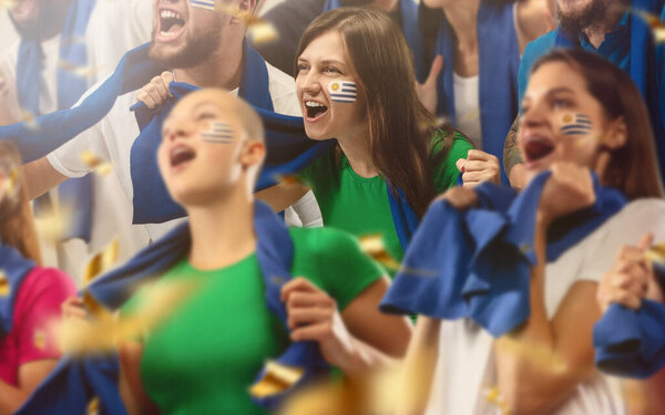 Uruguayan football, soccer fans cheering their team with a blue scarfs at stadium. Excited fans cheering a goal, supporting favourite players
