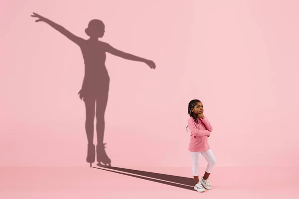 Childhood and dream about big and famous future. Conceptual image with girl and shadow of fit female figure skater on coral pink background — Stock Photo, Image