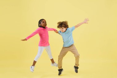 Çocukluk ve büyük ve ünlü bir gelecek hayal etmek. Sarı arka planda izole edilmiş küçük sevimli çocuklar.