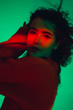 Kafkas kadın portresi, yeşil stüdyo arka planında çok renkli neon ışıklarla izole edilmiş.