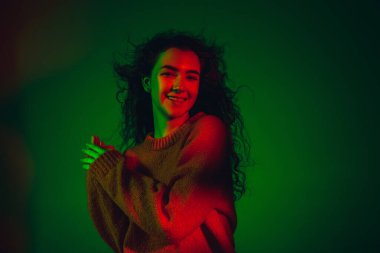 Kafkas kadın portresi, yeşil stüdyo arka planında çok renkli neon ışıklarla izole edilmiş.