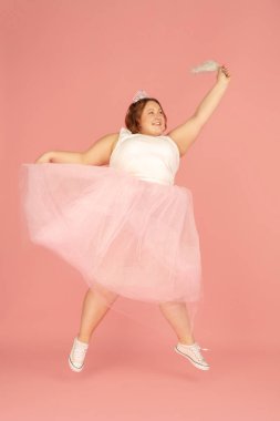 Pembe stüdyo arka planında izole edilmiş güzel bir beyaz artı beden modeli. Kapsama kavramı, insan duyguları, yüz ifadesi