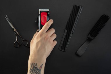 Siyah masa arkasına izole edilmiş ekipmanlı bir erkek berber..