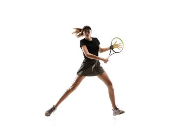 Beyaz arka planda tenis oynayan beyaz tenli genç beyaz kadın.