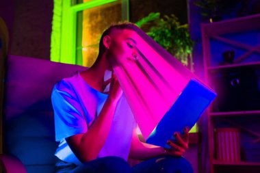 Neon ışıklı iç mekânda bir tablet kullanarak şık bir kadının sinematik portresi. Yüzü lekelenmiş, ekrana çekilmiş. Sosyal ağ bağımlılığı kavramı