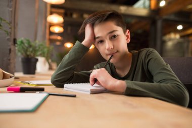 Küçük çocuk online video görüşmesi ve eğitim kursunda öğretmenini dinlerken masada oturuyor.