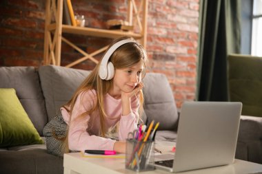 Grup çalışması yapan küçük bir kız öğretmeniyle video konferansı yapıyor, çevrimiçi kurslar dinliyor.