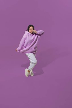 Mor stüdyo arka planında genç bir kadının yüksek açılı görüntüsü. Hareketli kız ya da hareket halinde. İnsan duyguları ve yüz ifadeleri kavramı