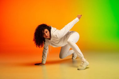 Neon ışıklarıyla dans salonundaki renkli arka planda hip-hop dansı yapan zarif beyaz kadın..